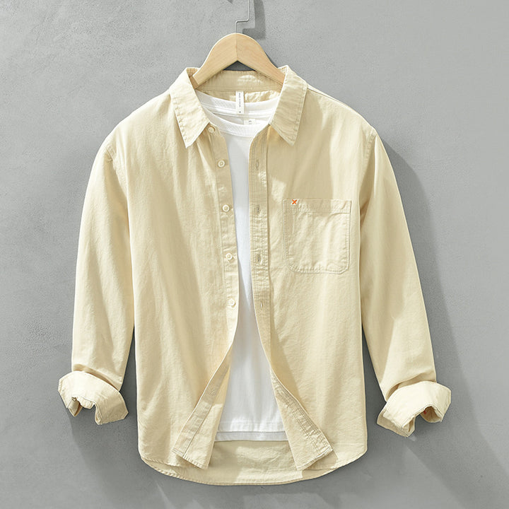 Herren Freizeithemd Cremefarbig aus 100% Baumwolle offen getragen als
Overshirt über einem weißen T-Shirt auf einem Holzbügel. Cheapseasons
Japanese Fresh Style.