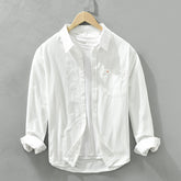 Herren Freizeithemd Weiß aus 100% Baumwolle offen getragen als
Overshirt über einem weißen T-Shirt auf einem Holzbügel. Cheapseasons
Japanese Fresh Style.