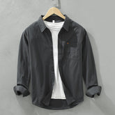 Herren Freizeithemd Schwarz aus 100% Baumwolle offen getragen als
Overshirt über einem weißen T-Shirt auf einem Holzbügel. Cheapseasons
Japanese Fresh Style.