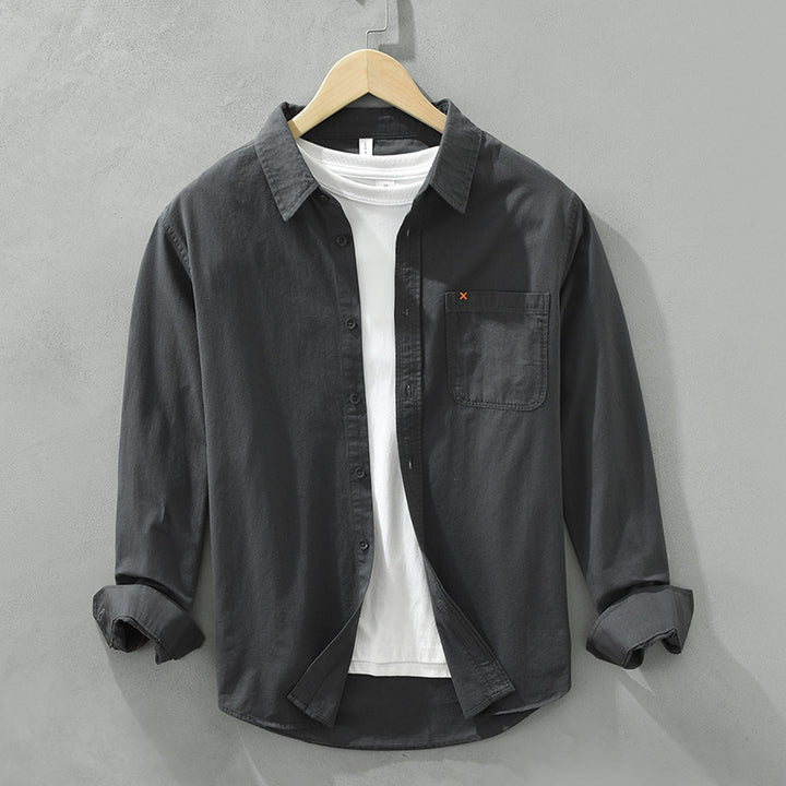 Herren Freizeithemd Schwarz aus 100% Baumwolle offen getragen als
Overshirt über einem weißen T-Shirt auf einem Holzbügel. Cheapseasons
Japanese Fresh Style.