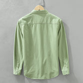 Herren Freizeithemd Salbeigrün aus 100% Baumwolle offen getragen als
Overshirt über einem weißen T-Shirt auf einem Holzbügel. Cheapseasons
Japanese Fresh Style.