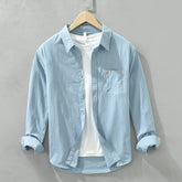 Herren Freizeithemd Hellblau aus 100% Baumwolle offen getragen als
Overshirt über einem weißen T-Shirt auf einem Holzbügel. Cheapseasons
Japanese Fresh Style.