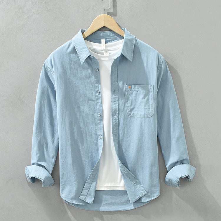 Herren Freizeithemd Hellblau aus 100% Baumwolle offen getragen als
Overshirt über einem weißen T-Shirt auf einem Holzbügel. Cheapseasons
Japanese Fresh Style.